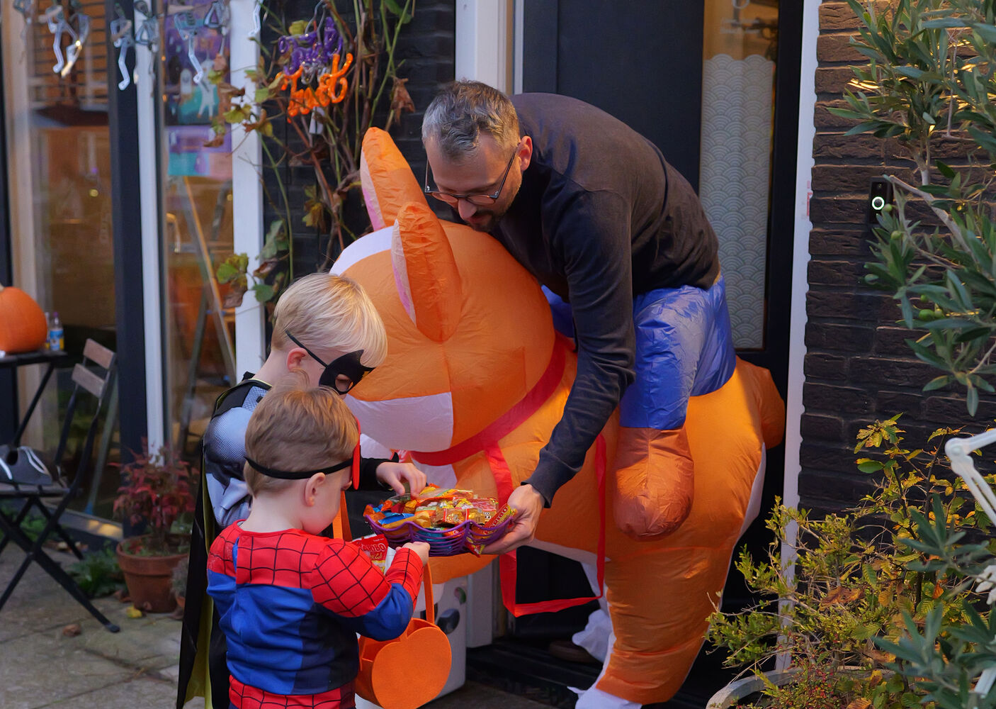 Twee jongetjes verkleed als Batman en Superman krijgen snoep van de man van Jobien. Hij is verkleed als Corgi (hond).