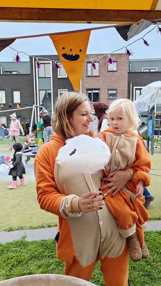Jobien staat met een suikerspin en haar hand en haar dochter Jessie op haar arm.