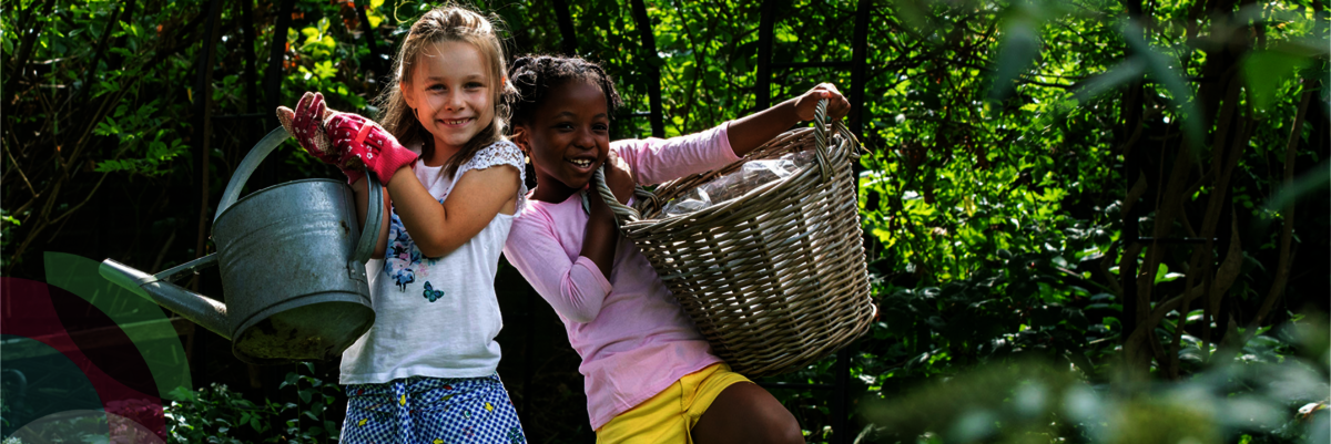 Twee meisjes staan tegen elkaar aan in de tuin met tuingereedschap en een gieter in de hand