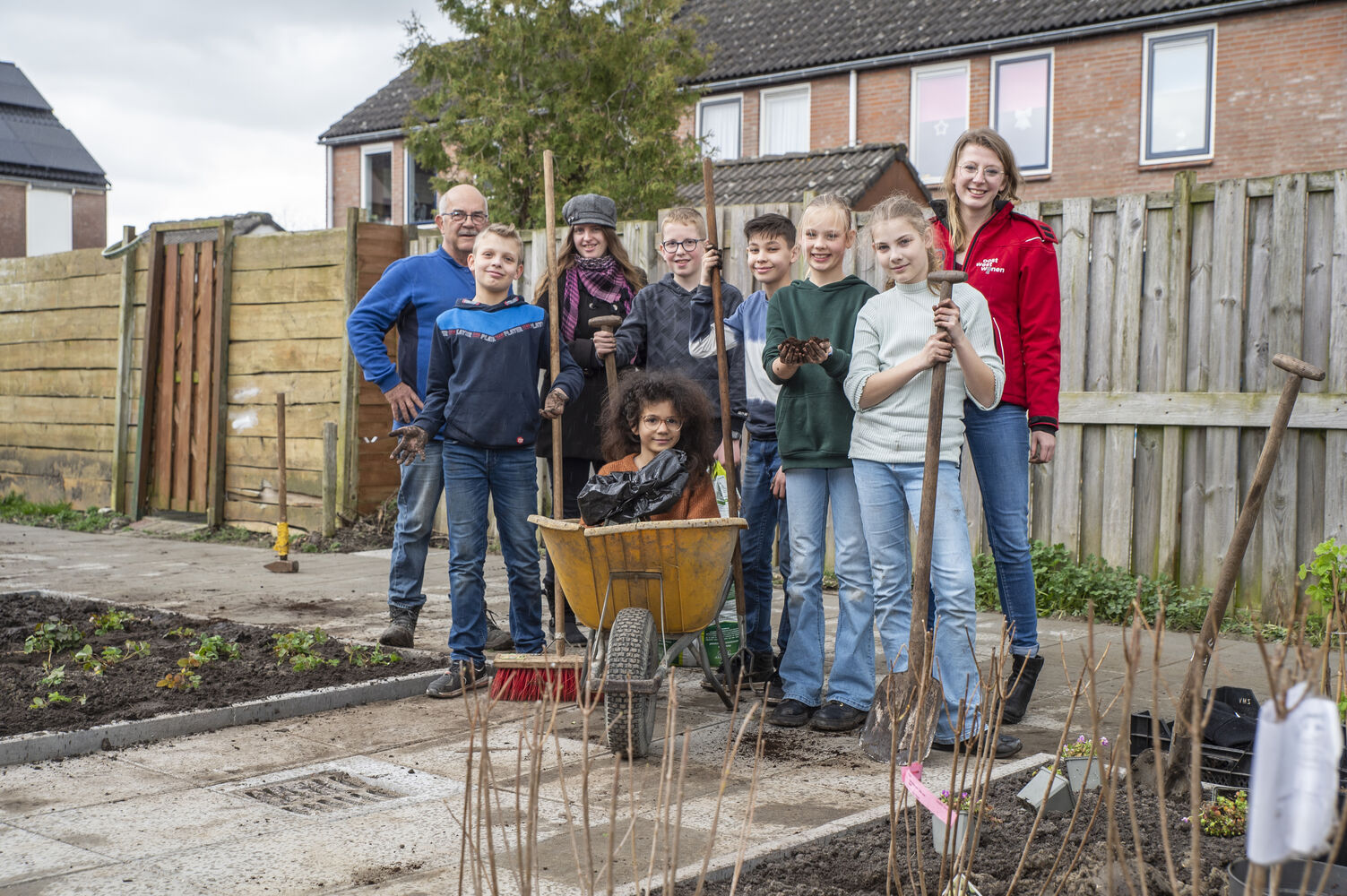 Een beeld van de leerlingen van CBS de Bron in een tuin met Hilde Herrewijnen, consulent duurzaamheid en wonen bij Oost West Wonen.­­
